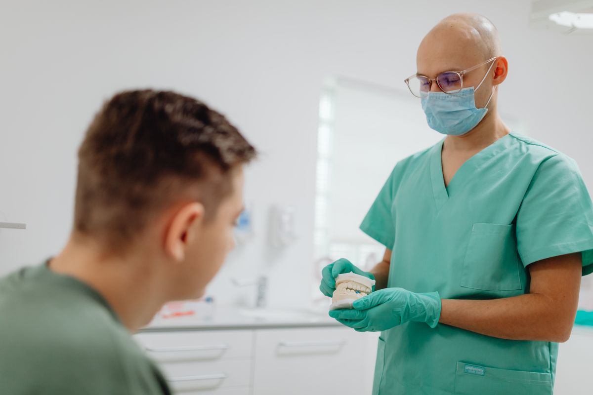 Dentist explaining implant treatment to a patient using a dental model
