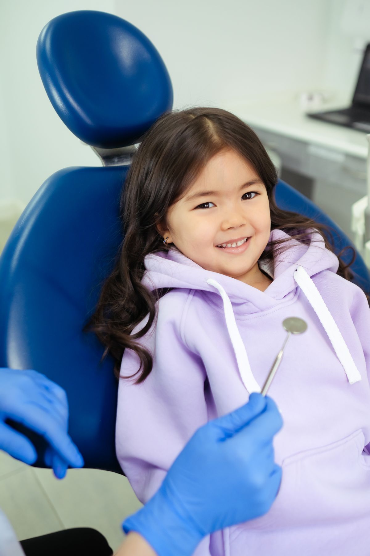 Happy young girl sitting in the dental chair before her check-up